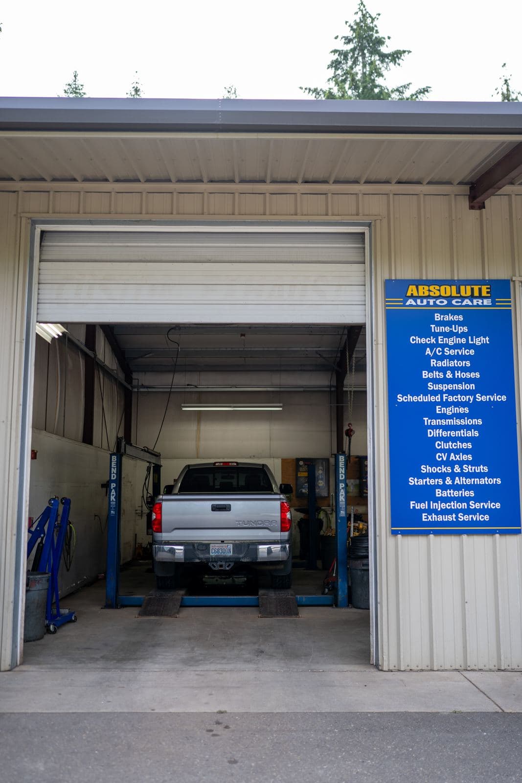 Open service bay door with a truck on the lift at Absolute Auto Care