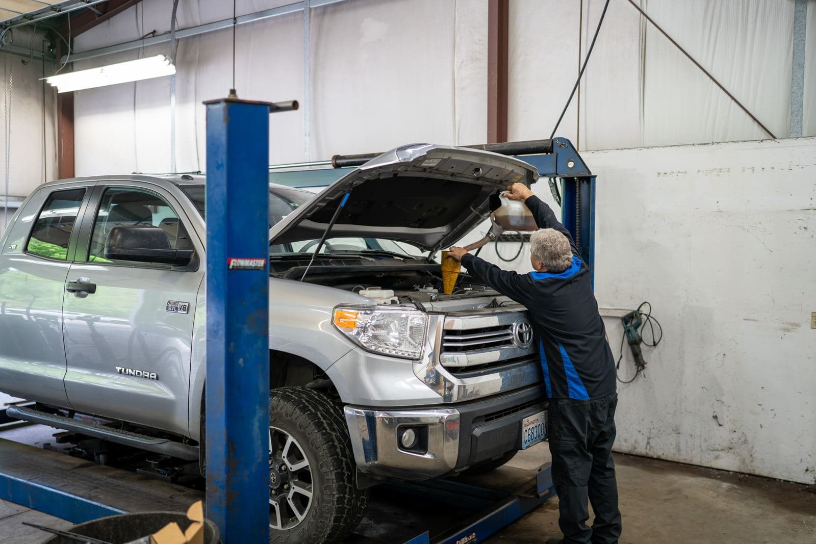 Technician working under the hood of a Toyota Tundra on the lift