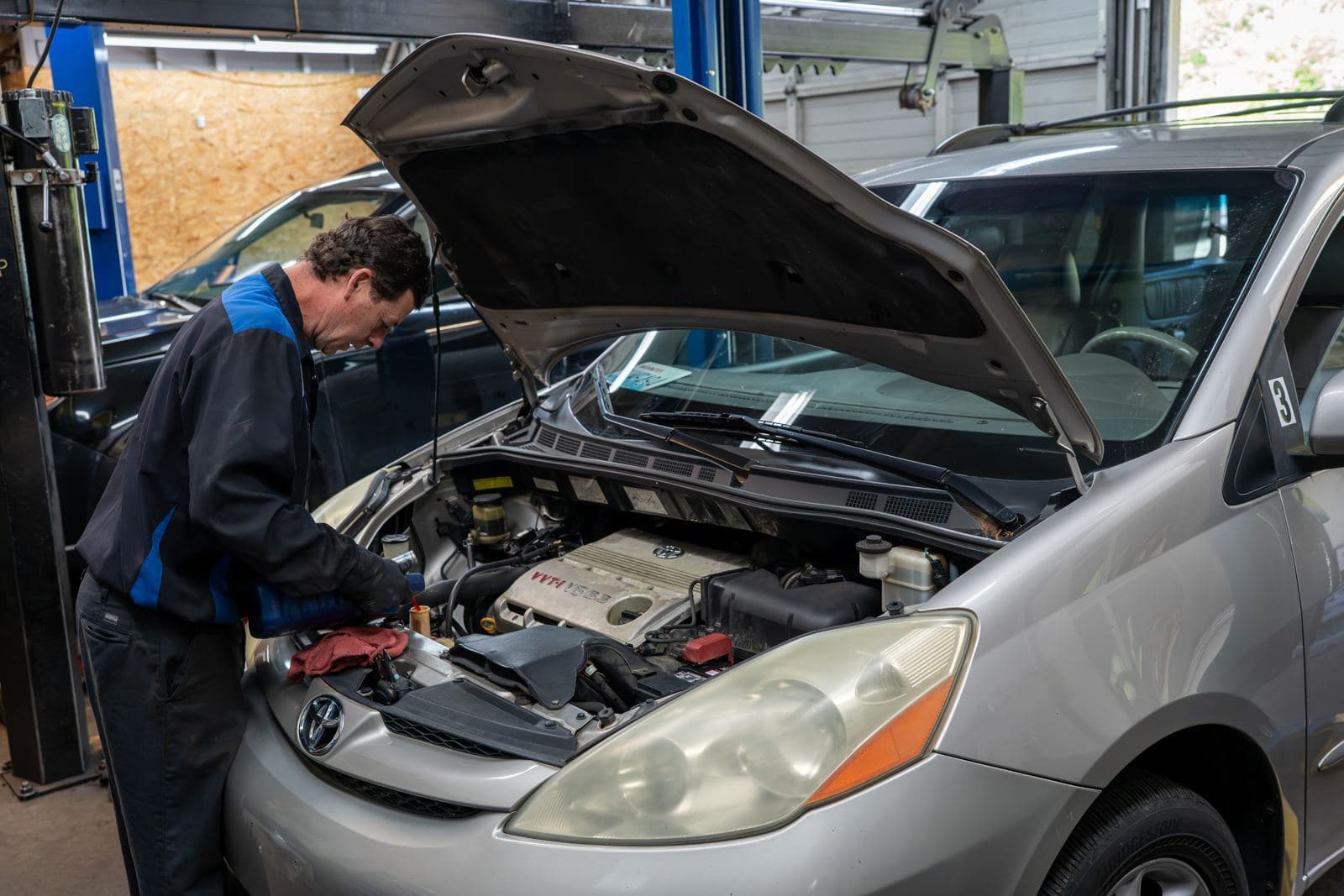 Technicians diagnosing a minivan engine with the hood up