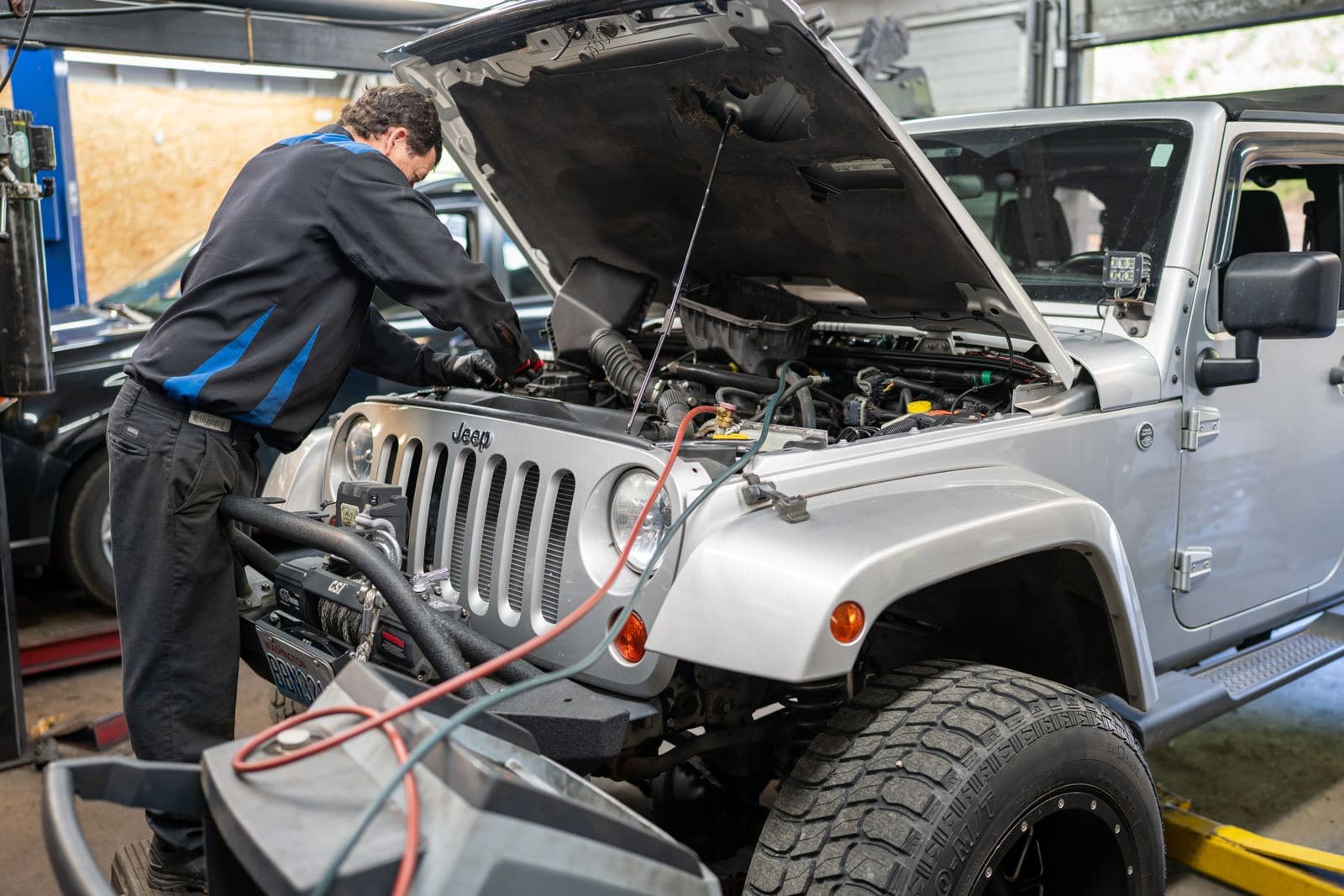 Technician working under the hood of a Jeep Wrangler