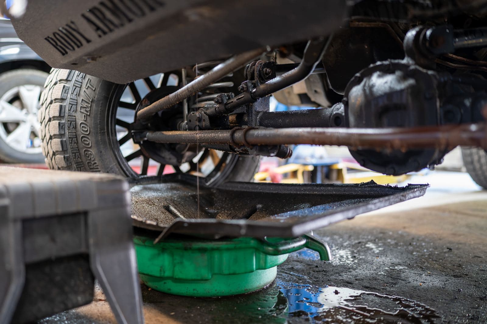 Underside of a lifted Jeep during a fluid service