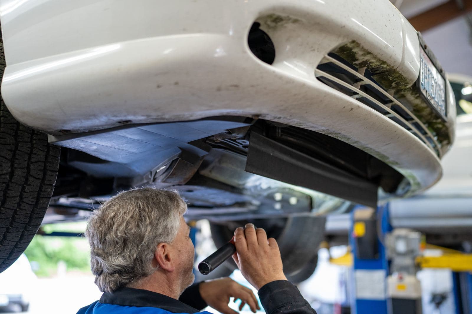 Technician inspecting an engine bay and vehicle underside
