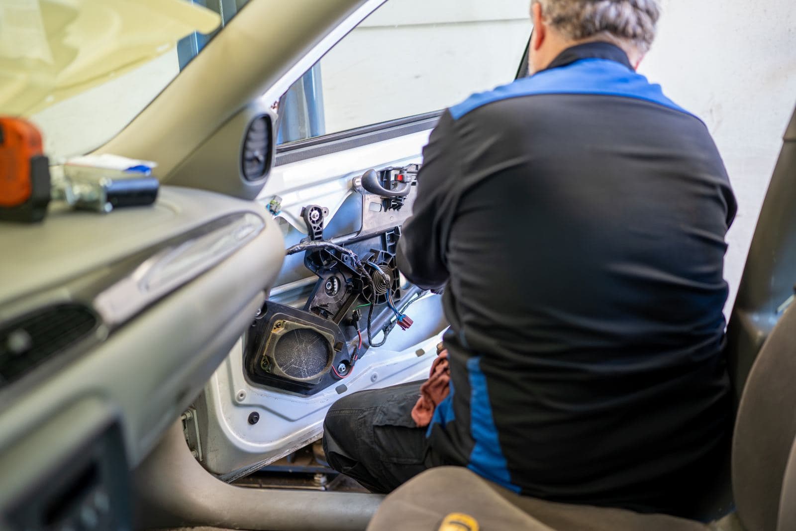 Technician working on a door panel from inside the vehicle
