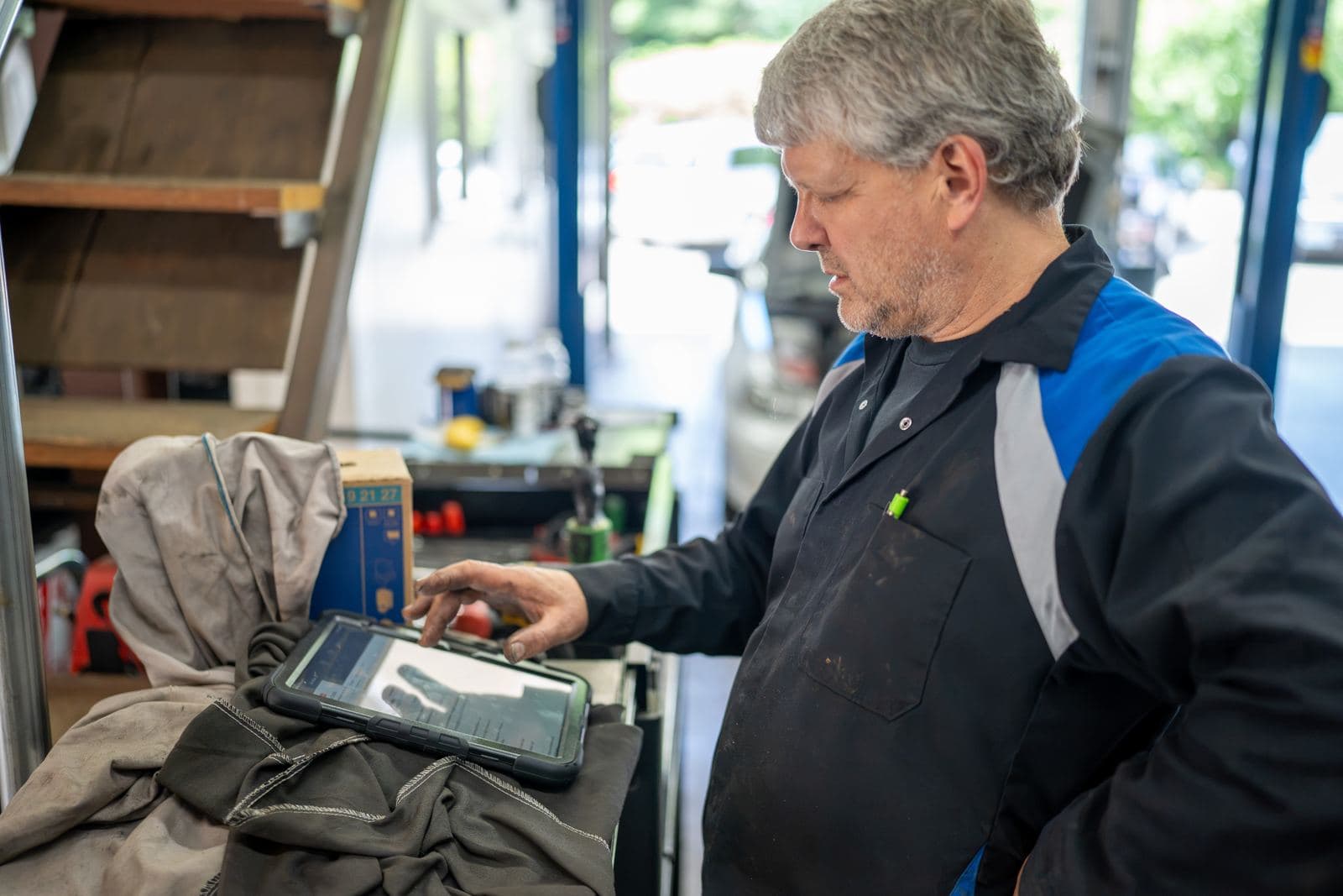 Technician checking a repair order on a tablet at the workbench
