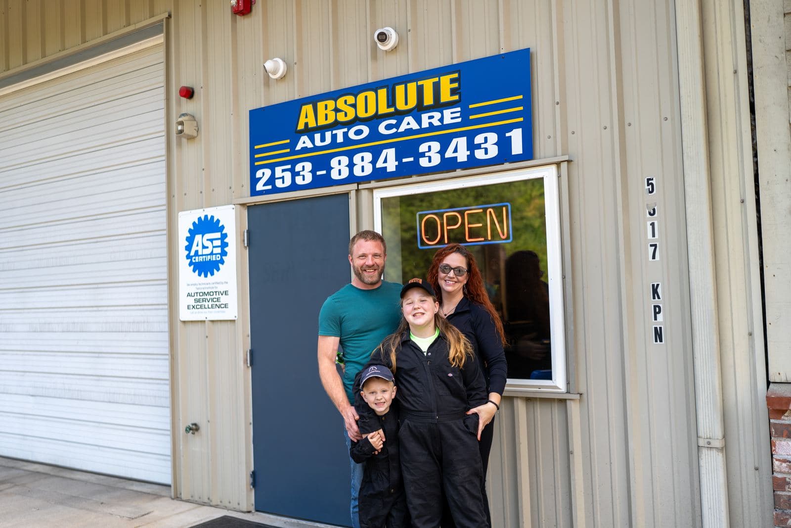 The Absolute Auto Care family in front of the shop sign