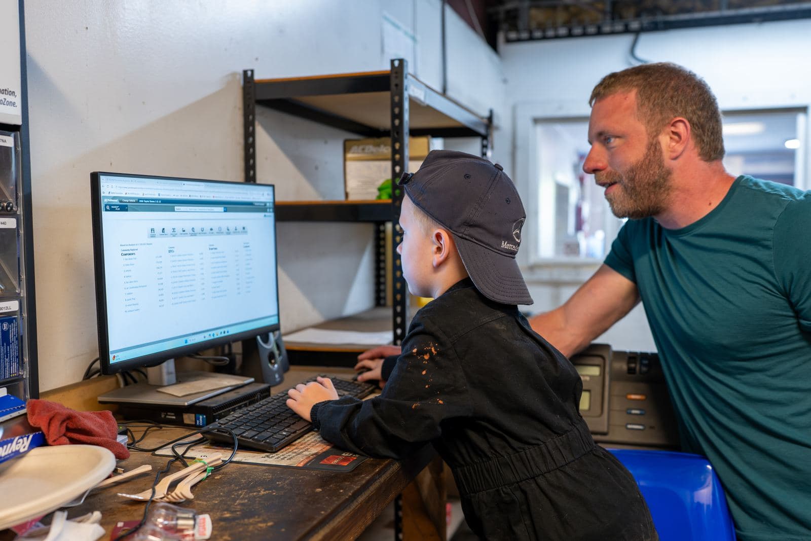 Shop owner showing a junior crew member the shop computer