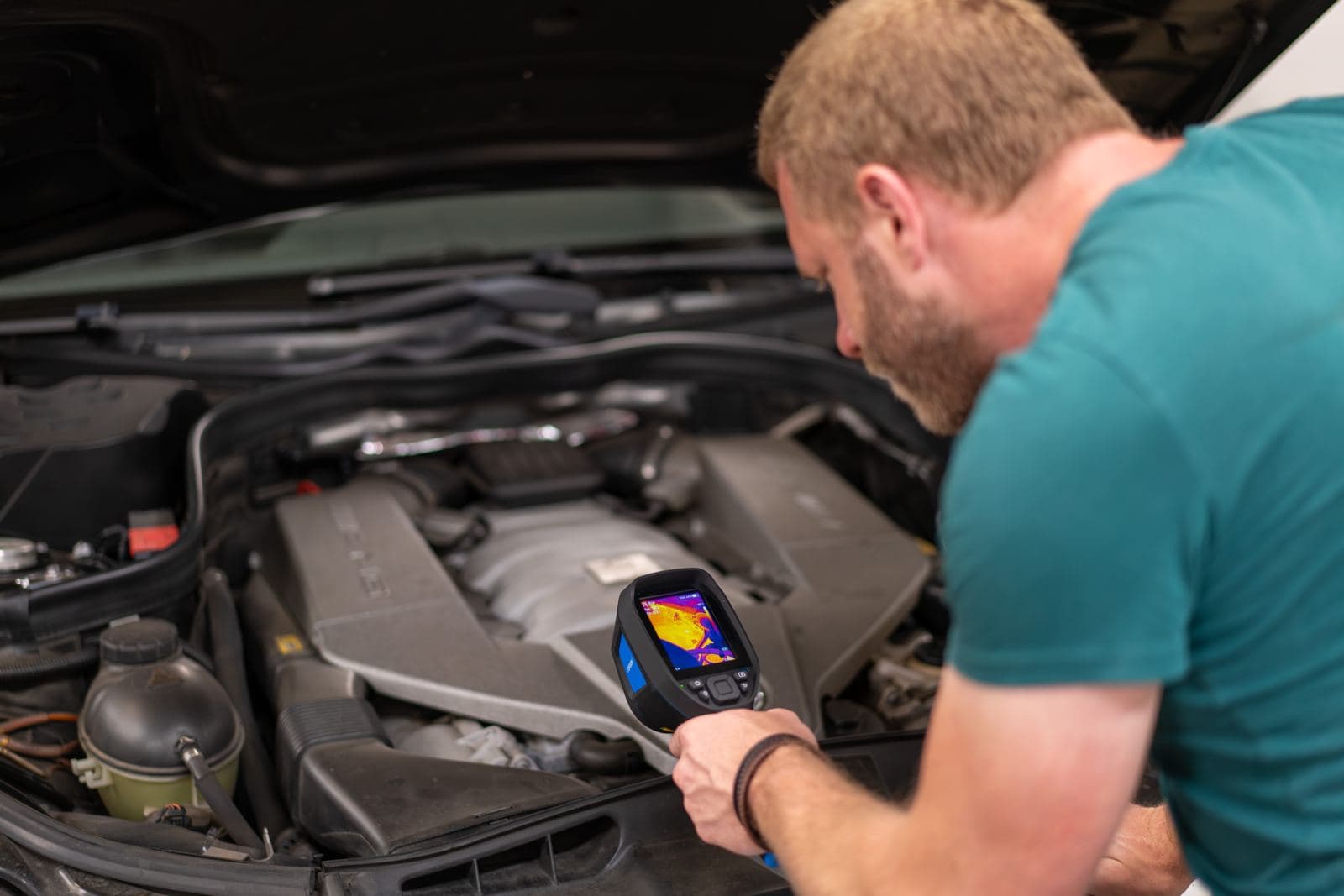 Technician using a thermal imaging camera to diagnose a vehicle