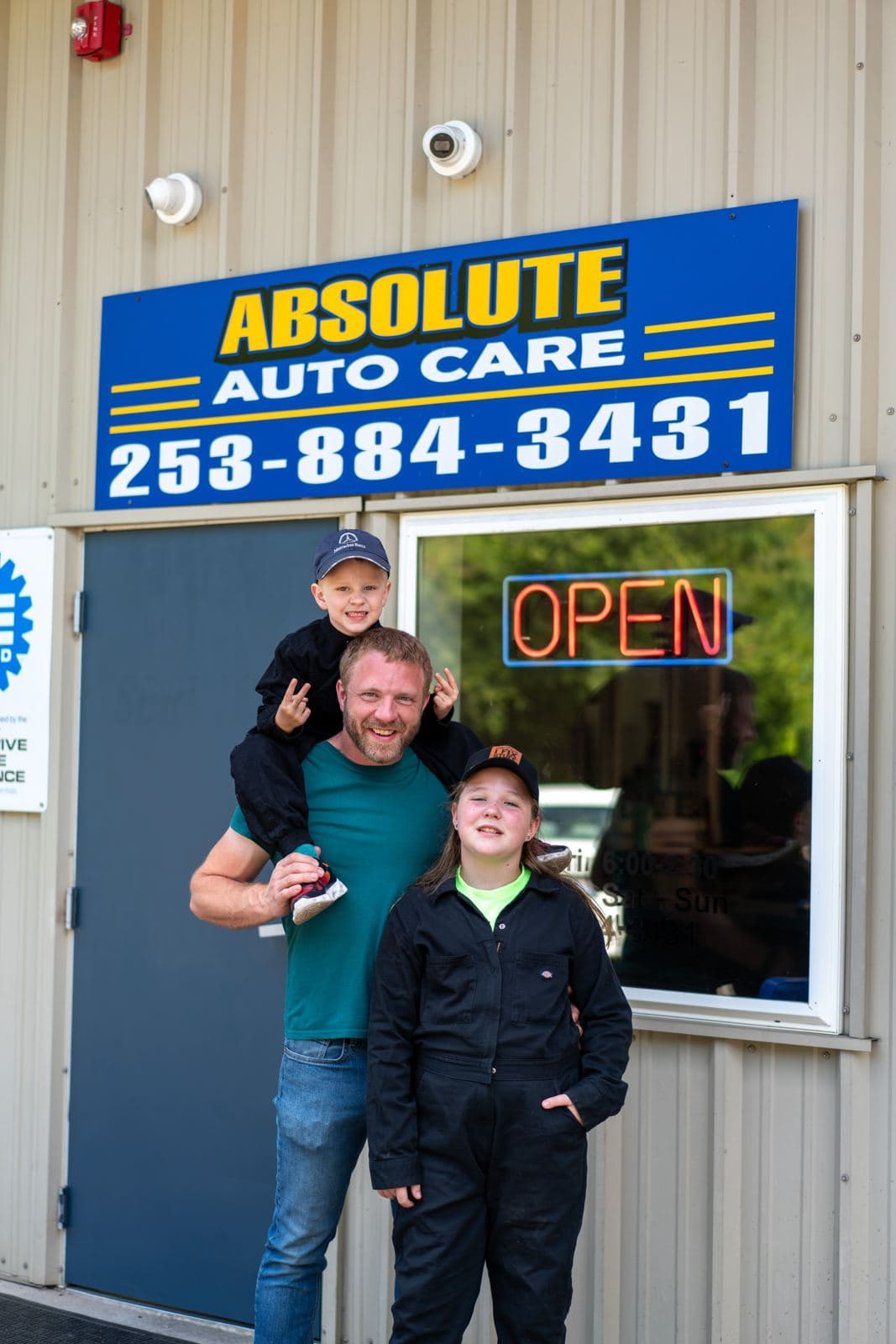 The Absolute Auto Care family in front of the shop sign