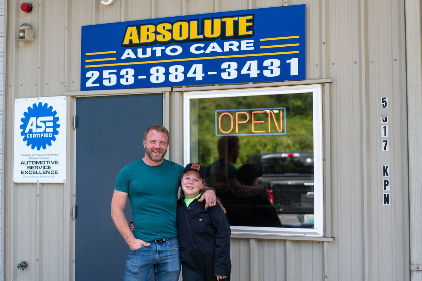 The Absolute Auto Care family in front of the shop sign