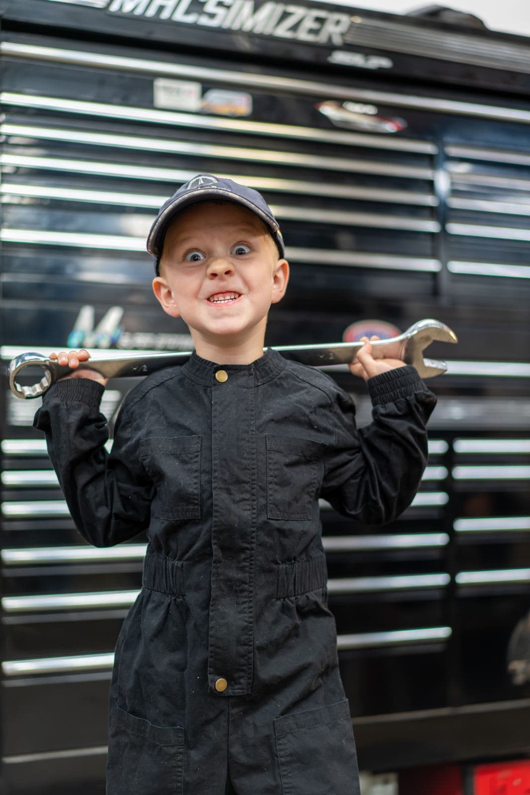 Junior crew members posing with wrenches by the tool chest